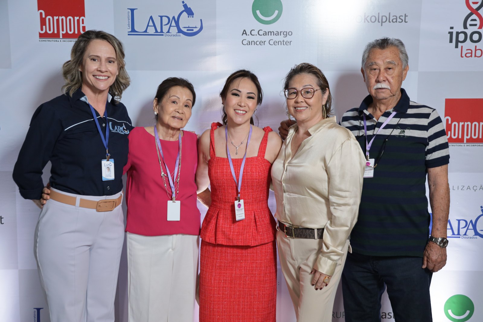 Integrante da equipe do LAPAC com quatro participantes em frente ao painel do simpósio