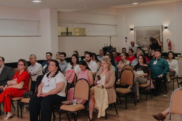 Plateia sentada no salão do hotel acompanha uma palestra