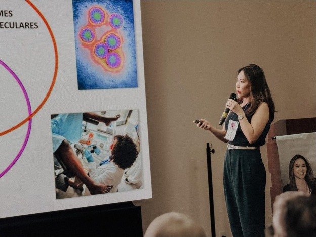 Palestrante com microfone ao lado do telão, durante a apresentação